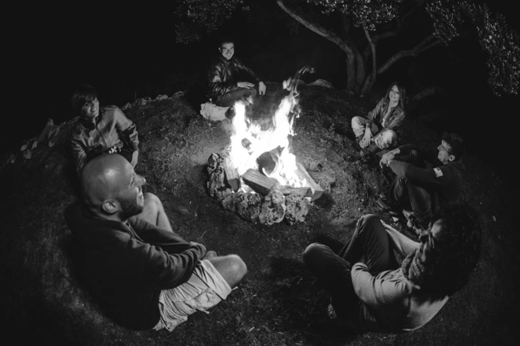 Image of people sharing stories and communicating to build consensus facilitated by a campfire