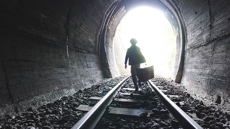 Image showing a child walking in railway tunnel towards the light and his future on a journey. This is symbolic of the Organisational learning and change, people development and visioning that Bats facillitate