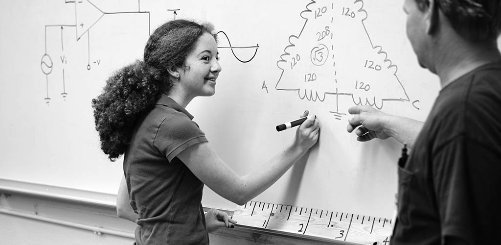 Image of young women sharing technical knowledge with customers on whiteboard